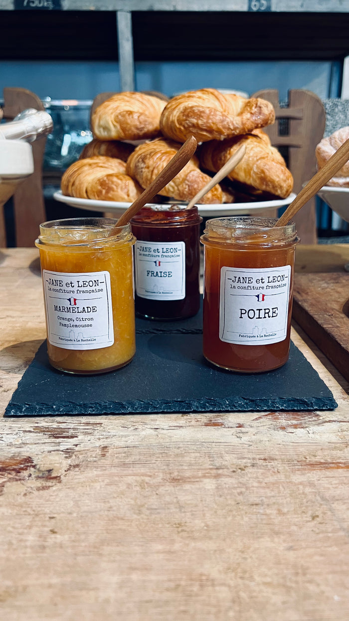 Three jam jars with black lids and cream labels on a tabletop.