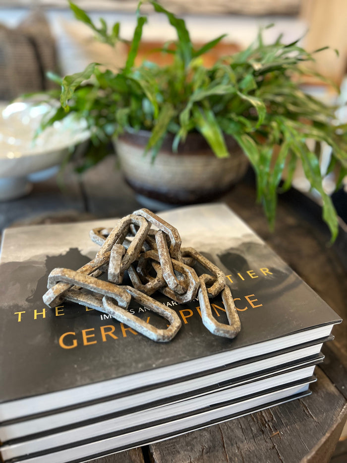 Antique-style metal chain draped over stacked books, dark weathered links