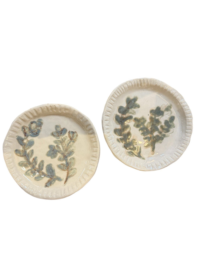 Set of two round white plates with scalloped rim and blue-green botanical leaf pattern