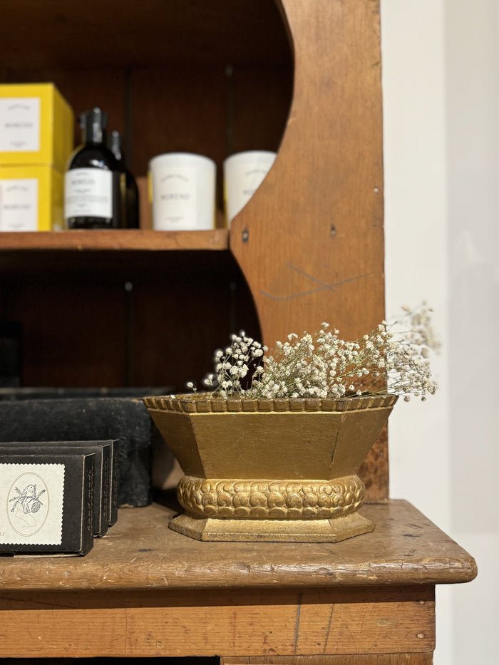 Brass cast-iron urn planter with gold ridged base and small white flowers