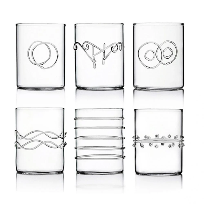 Six Deco Clear Water Glasses by Ichendorf Milano, each made from sturdy borosilicate glass and adorned with distinctive raised patterns—such as loops, waves, rings, parallel lines, and dots—are arranged in two rows on a plain white background.