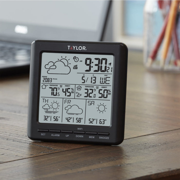 Close-up of a Taylor digital weather forecaster on a wooden table showing the large display