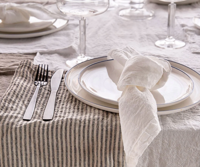 Folded linen napkin on table setting with plate and cutlery nearby