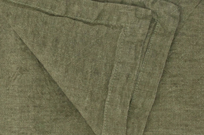 Olive green linen napkin with stitched hem and neatly folded corner