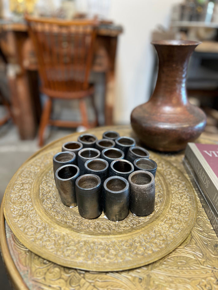 Vintage brass Moroccan tray with engraved edge, holding dark metal candle holders