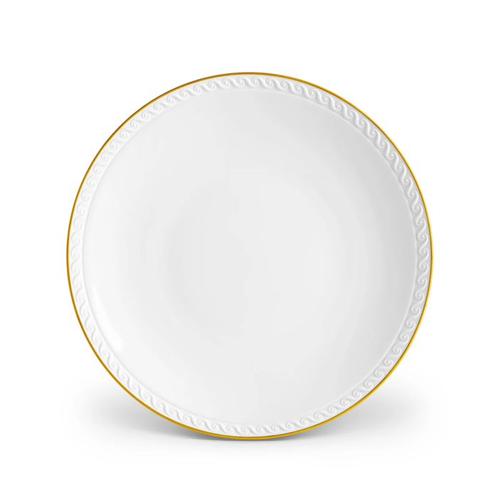 The L’Objet Neptune Gold dinnerware plate is crafted from fine white porcelain with a 24k gold rim and a textured wave pattern along the edge, displayed against a white background.