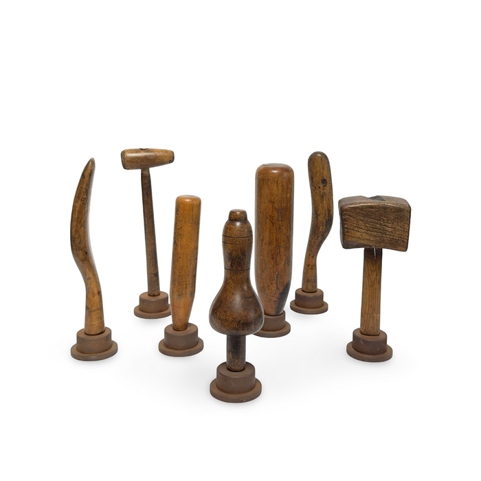 Set of primitive wooden hand tools on circular bases, varied hammer and pick shapes