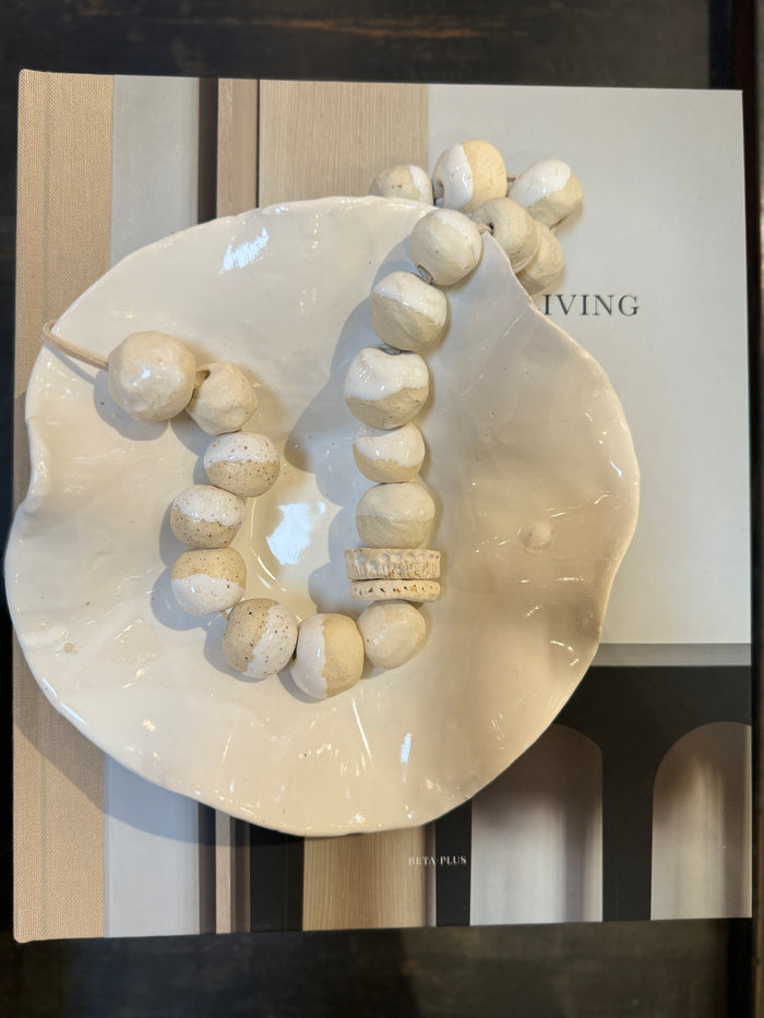 Off-white leaf-shaped catchall bowl with glossy glaze and scalloped rim